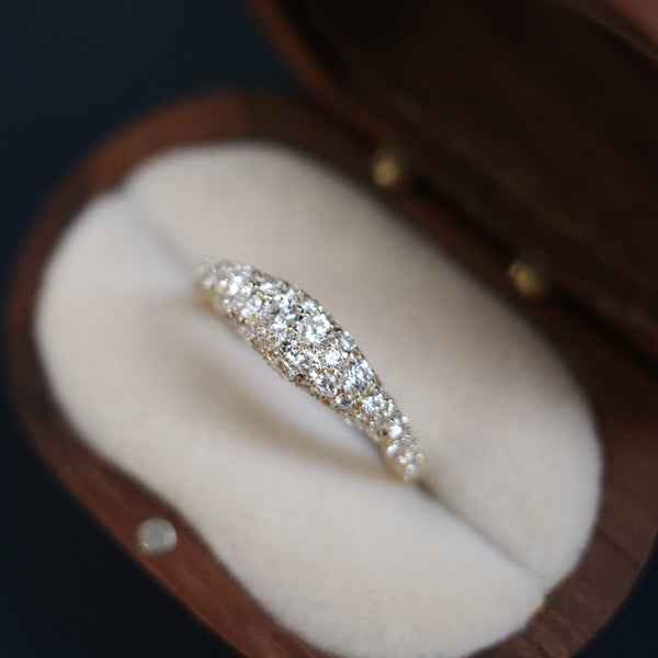 A diamond ring with a curved, pavé-set band in a yellow gold setting.