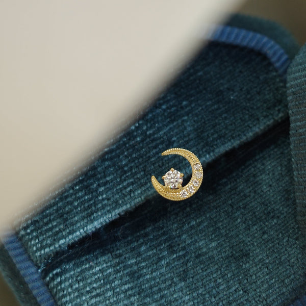 A mini gold crescent moon stud earring with a natural diamond.